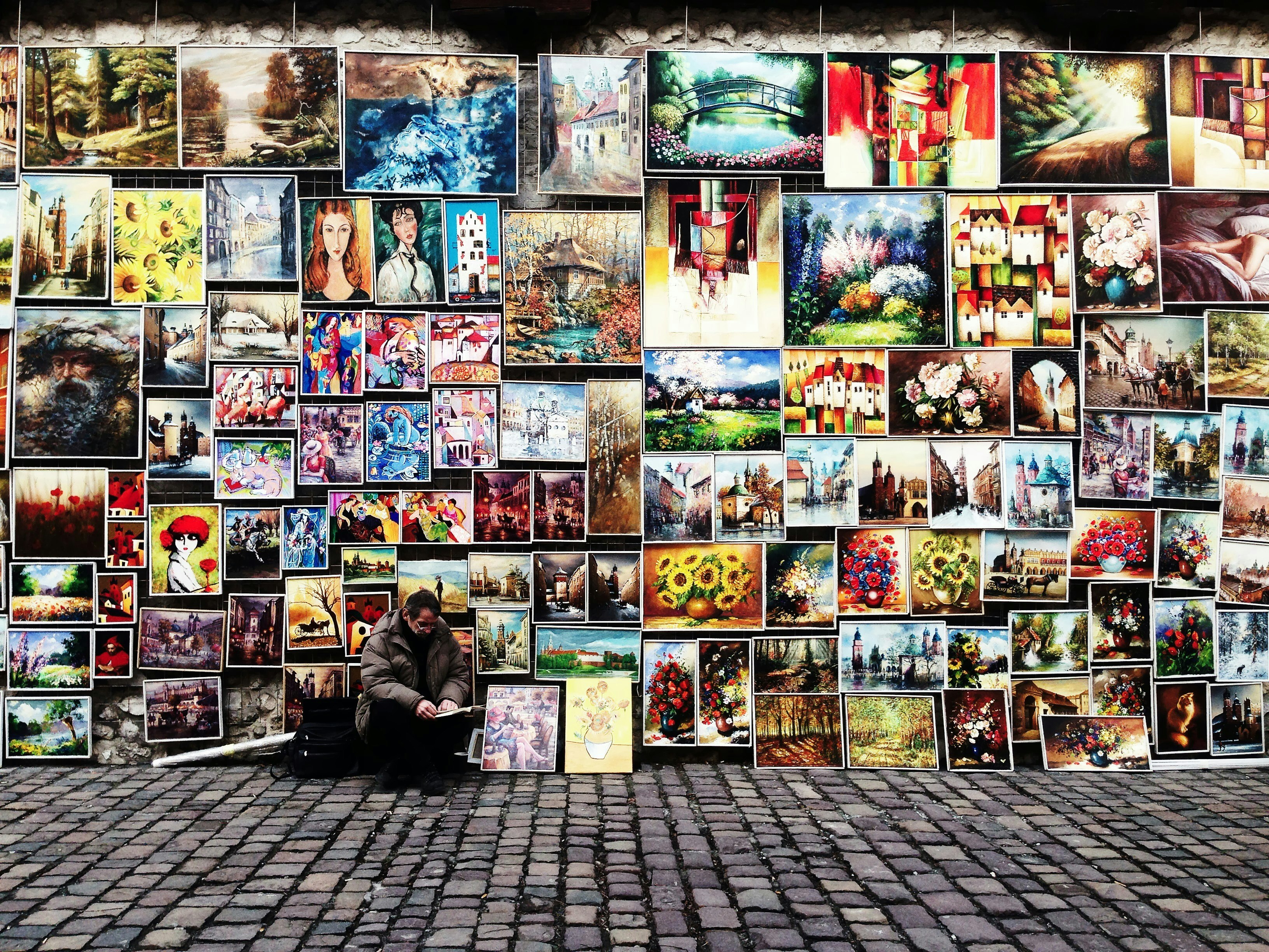 man sitting beside painting lot